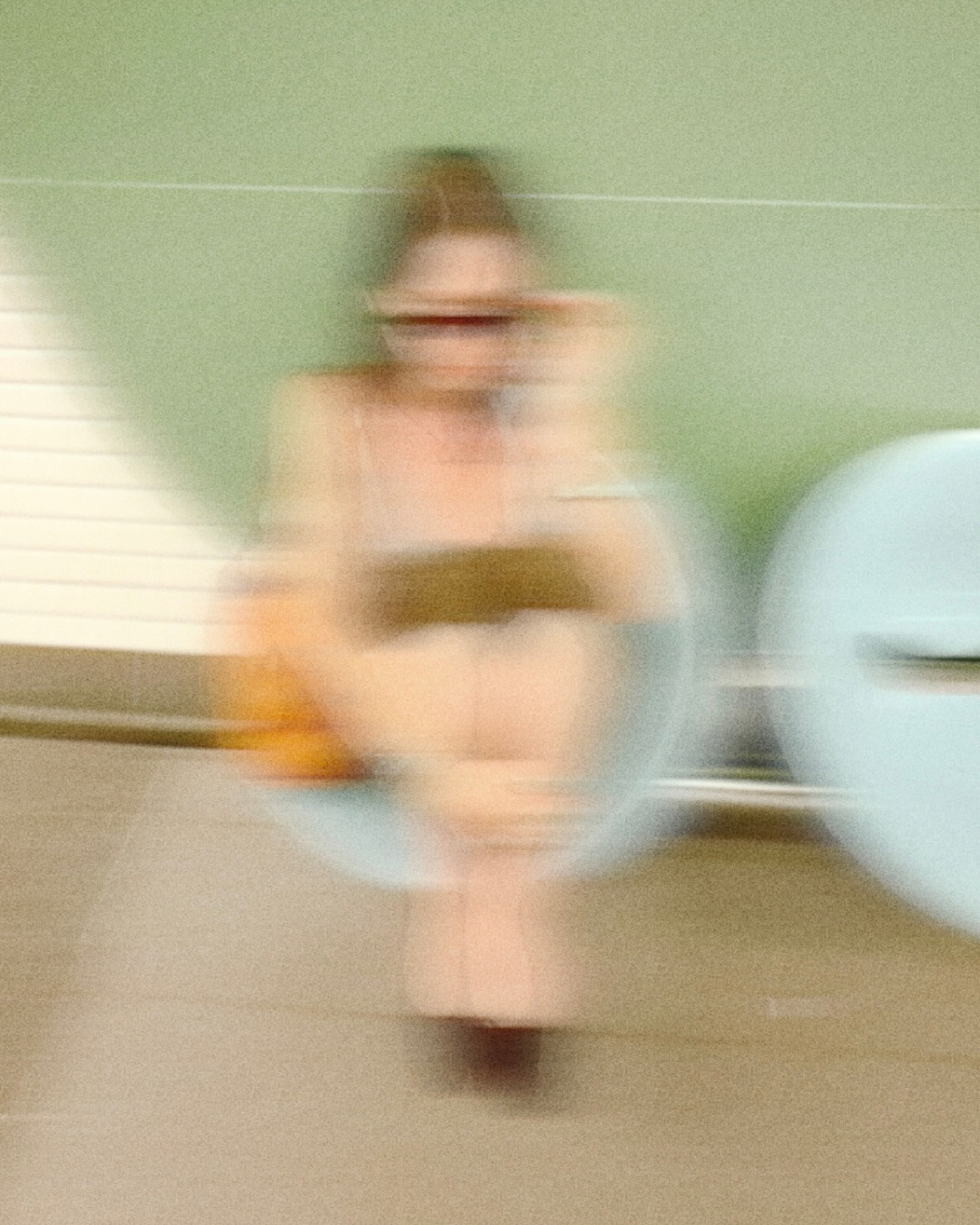 Caroline seated in a powder-blue chair in front of a green wall